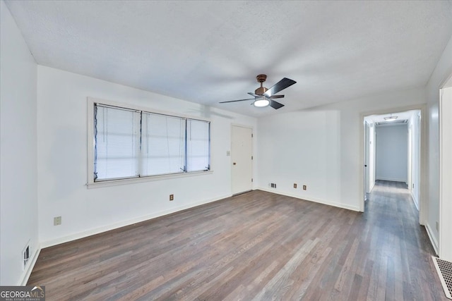 empty room with visible vents, baseboards, a ceiling fan, and wood finished floors