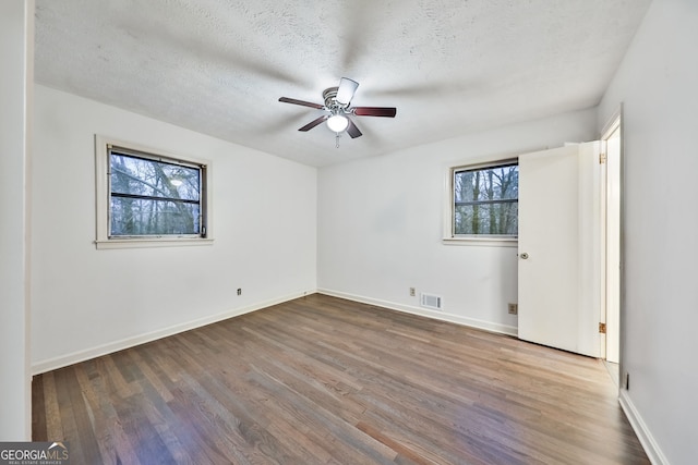 spare room with ceiling fan, baseboards, wood finished floors, and visible vents
