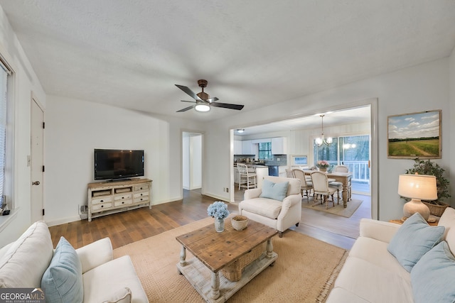 living area with wood finished floors, a ceiling fan, and baseboards