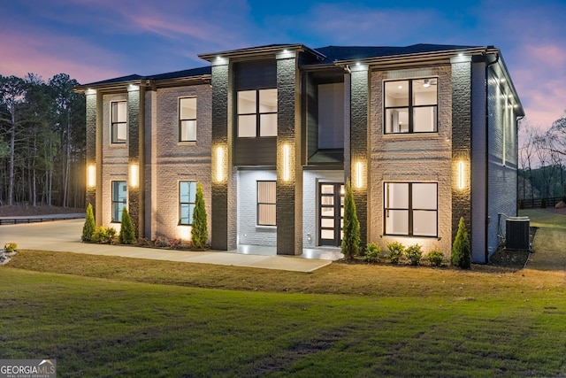 view of front of home with central AC unit and a front yard