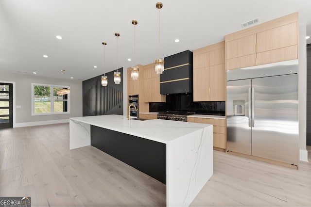 kitchen with light brown cabinetry, appliances with stainless steel finishes, modern cabinets, visible vents, and extractor fan