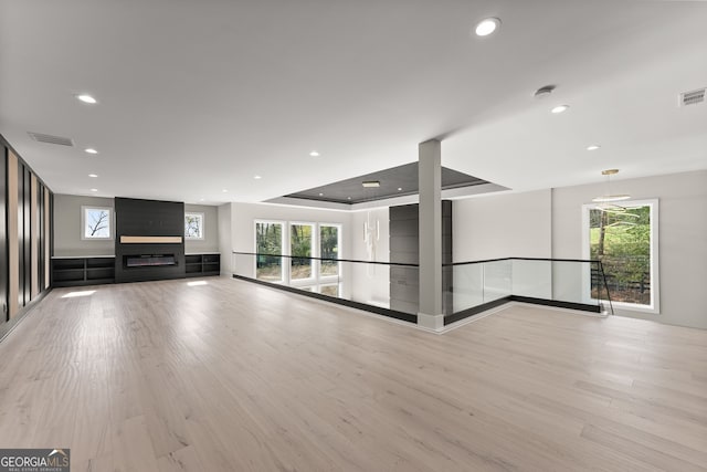 unfurnished living room featuring a wealth of natural light, visible vents, and light wood-type flooring
