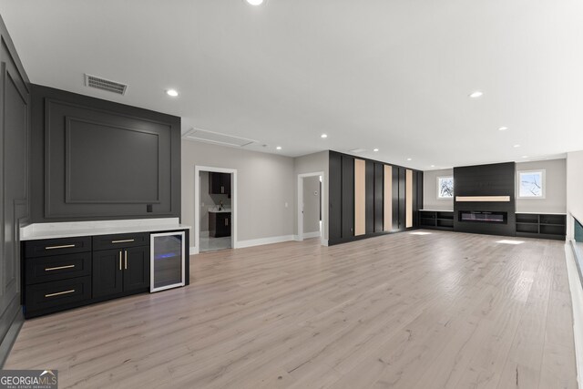 unfurnished living room with recessed lighting, baseboards, wine cooler, light wood-style floors, and visible vents