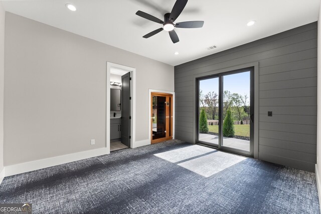 unfurnished bedroom with carpet flooring, wood walls, access to exterior, and recessed lighting
