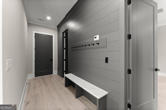 mudroom featuring wooden walls, crown molding, light wood-style floors, and visible vents