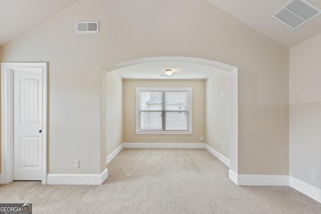 carpeted spare room with arched walkways, visible vents, baseboards, and vaulted ceiling