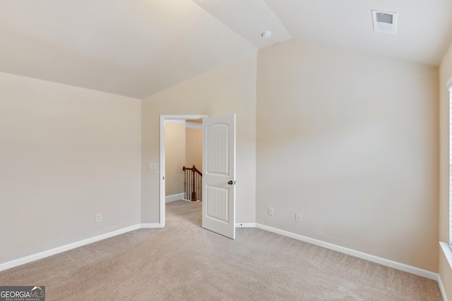 unfurnished room with light carpet, baseboards, lofted ceiling, and visible vents