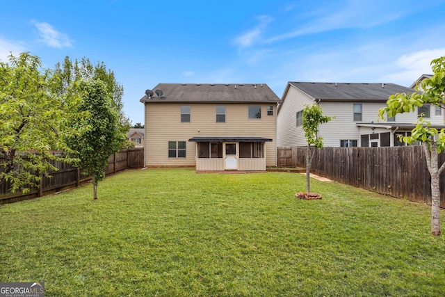 rear view of house featuring a fenced backyard, a sunroom, and a lawn