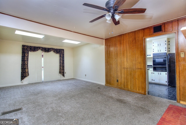 empty room featuring carpet floors, ceiling fan, and visible vents