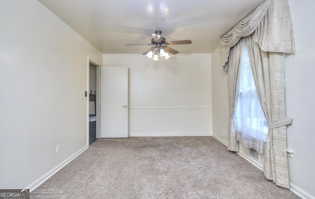 carpeted spare room featuring baseboards, visible vents, and ceiling fan