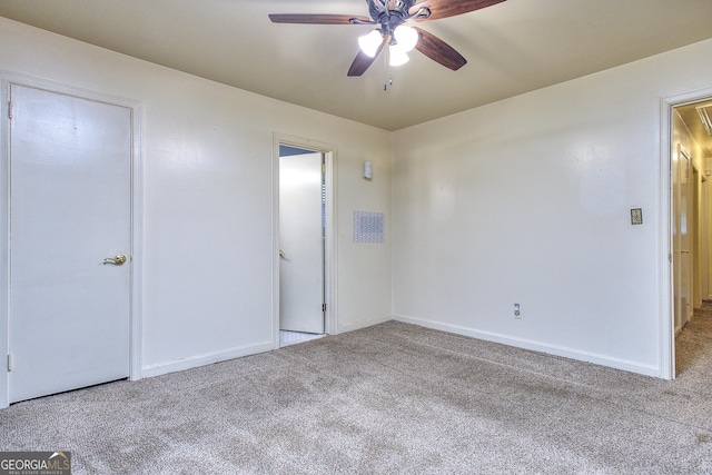 carpeted spare room featuring attic access, baseboards, and a ceiling fan