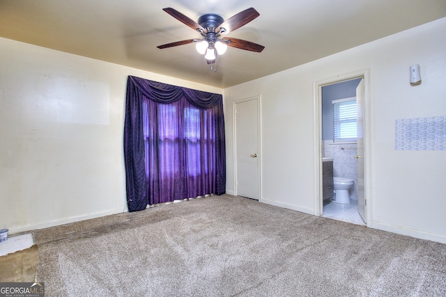 unfurnished bedroom with baseboards, ensuite bath, ceiling fan, and carpet