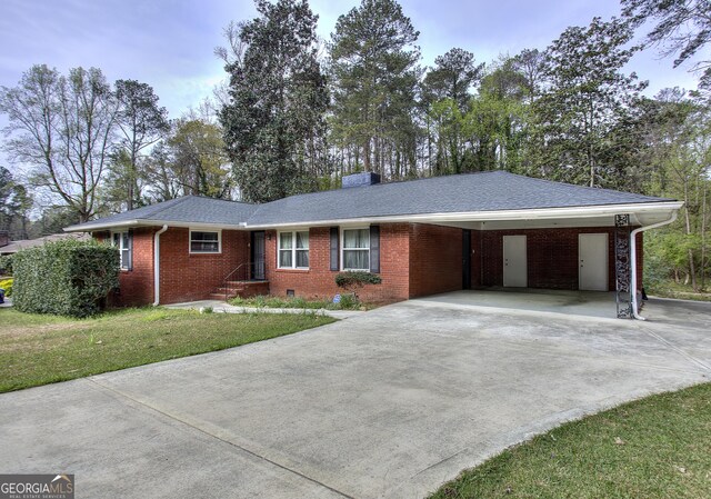 single story home featuring an attached carport, brick siding, concrete driveway, and a front yard