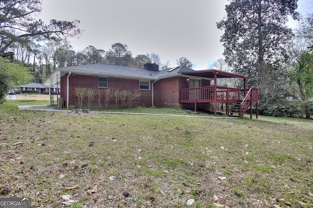 back of property with a deck, brick siding, and a yard