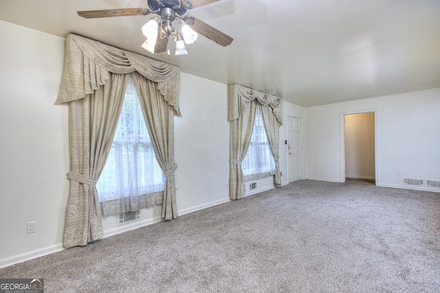 carpeted spare room with baseboards, visible vents, and a ceiling fan