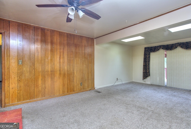 carpeted empty room with wooden walls and ceiling fan