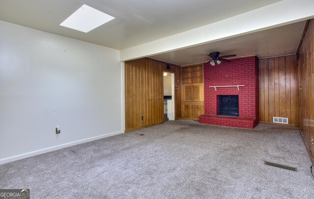unfurnished living room with visible vents, wood walls, carpet flooring, and a fireplace