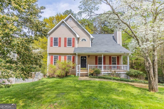 view of front of house with covered porch, a front yard, roof with shingles, and a chimney