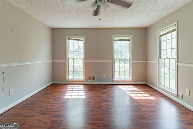 unfurnished room featuring a healthy amount of sunlight, visible vents, wood finished floors, and a ceiling fan