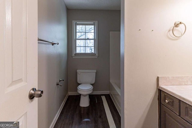bathroom featuring vanity, toilet, a washtub, baseboards, and wood finished floors