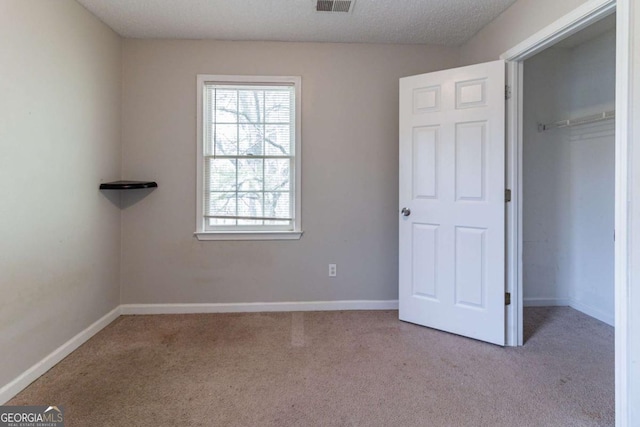 unfurnished bedroom with a closet, a textured ceiling, visible vents, baseboards, and carpet floors