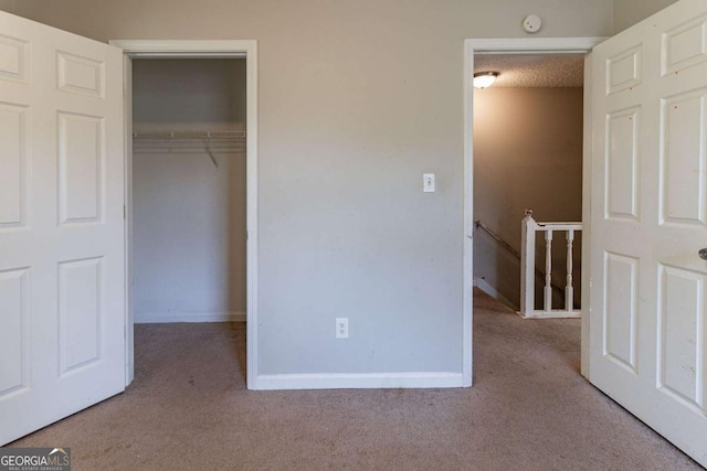 unfurnished bedroom with baseboards, a closet, carpet, and a textured ceiling