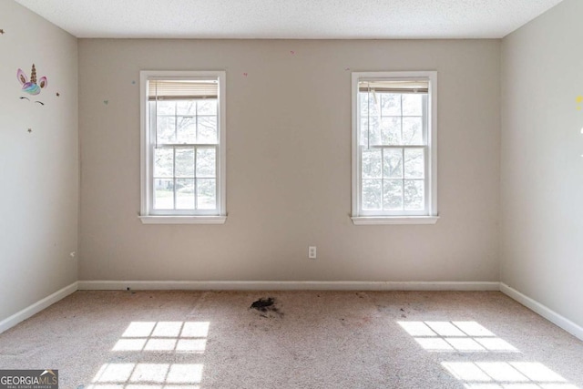 carpeted spare room with baseboards and a textured ceiling