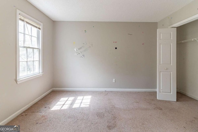 unfurnished bedroom featuring a closet, carpet flooring, a textured ceiling, and baseboards