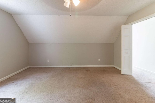 bonus room featuring a textured ceiling, baseboards, a ceiling fan, light carpet, and vaulted ceiling