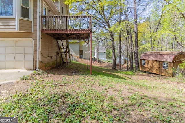 view of yard with stairway, a wooden deck, an outbuilding, a storage shed, and a garage
