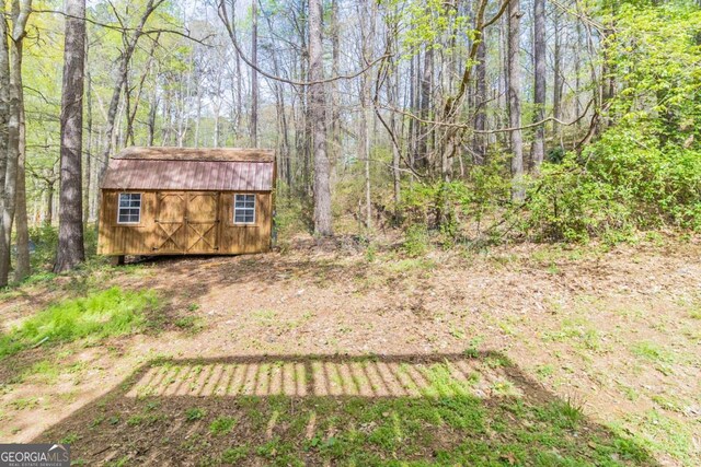 view of yard with a wooded view, a storage unit, and an outdoor structure