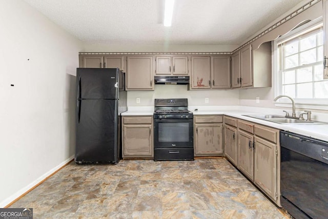 kitchen with light countertops, under cabinet range hood, baseboards, a sink, and black appliances