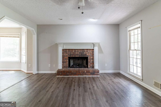 unfurnished living room with dark wood-style floors, visible vents, ceiling fan, and baseboards