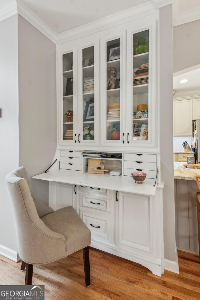interior space featuring light wood-style flooring, ornamental molding, and baseboards