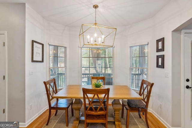 dining space with baseboards, a wealth of natural light, an inviting chandelier, and light wood finished floors
