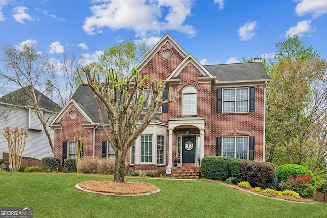view of front of house featuring brick siding, roof with shingles, and a front lawn