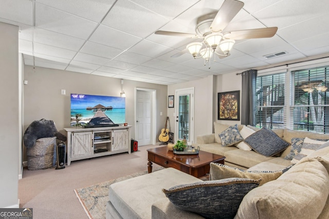carpeted living room featuring visible vents, a drop ceiling, and a ceiling fan