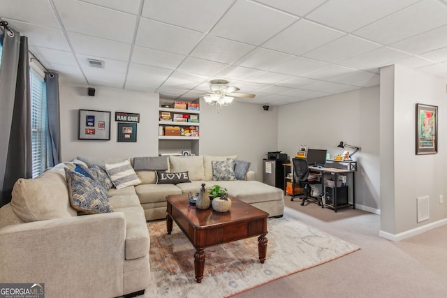 carpeted living area featuring baseboards, visible vents, ceiling fan, and a paneled ceiling