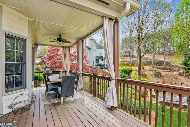 wooden terrace featuring outdoor dining space and ceiling fan