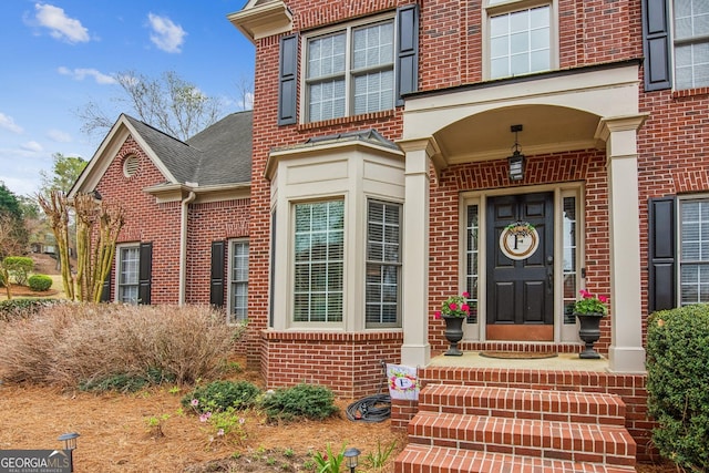 property entrance featuring brick siding and roof with shingles
