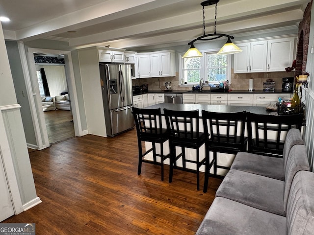 kitchen featuring appliances with stainless steel finishes, decorative backsplash, dark countertops, and dark wood-style floors