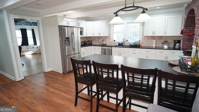 kitchen featuring appliances with stainless steel finishes, ornamental molding, dark wood finished floors, a healthy amount of sunlight, and a sink