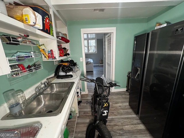 kitchen with dark wood-type flooring, visible vents, baseboards, and a sink