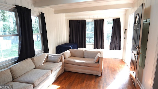 living area with beamed ceiling, wood finished floors, and a healthy amount of sunlight