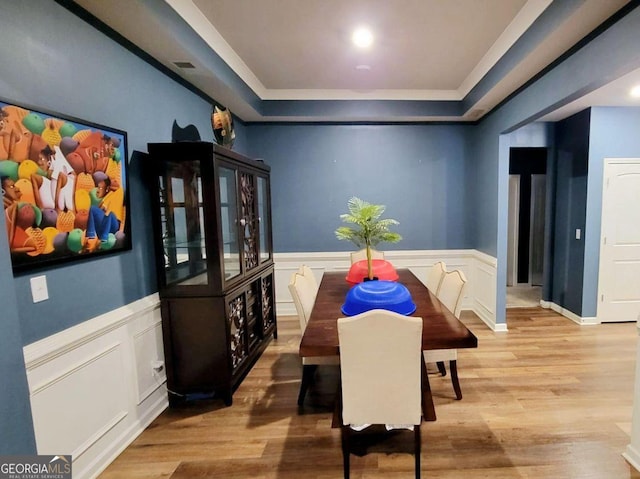 113 Citadel Dr, Hampton, GA 30228 - dining space with light wood finished floors, a tray ceiling, a decorative wall, wainscoting, and crown molding