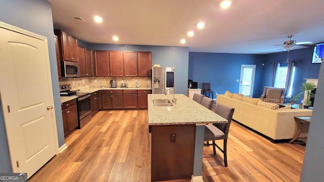 113 Citadel Dr, Hampton, GA 30228 - kitchen with appliances with stainless steel finishes, a breakfast bar, open floor plan, light wood-style floors, and decorative backsplash