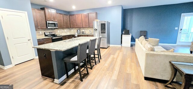 113 Citadel Dr, Hampton, GA 30228 - kitchen featuring stainless steel appliances, decorative backsplash, light wood-style flooring, a kitchen breakfast bar, and a center island with sink