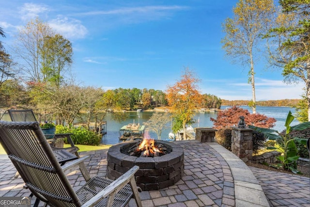 view of patio with an outdoor fire pit and a water view