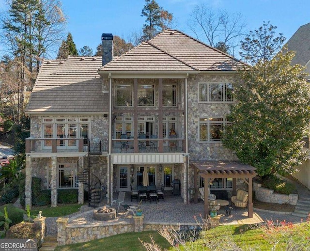 rear view of house with an outdoor fire pit, stone siding, a chimney, a pergola, and stairway