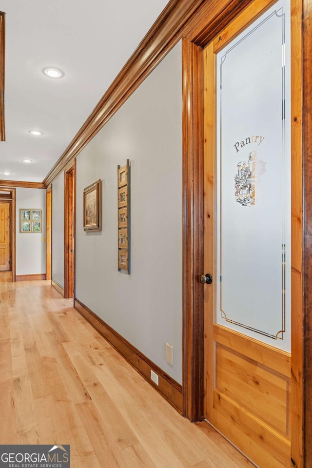 corridor with ornamental molding, light wood-style flooring, baseboards, and recessed lighting